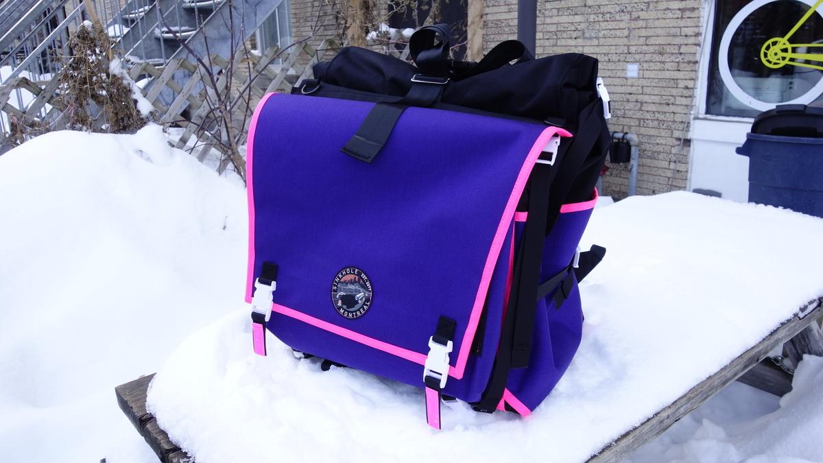 A black, purple and pink messenger backpack
