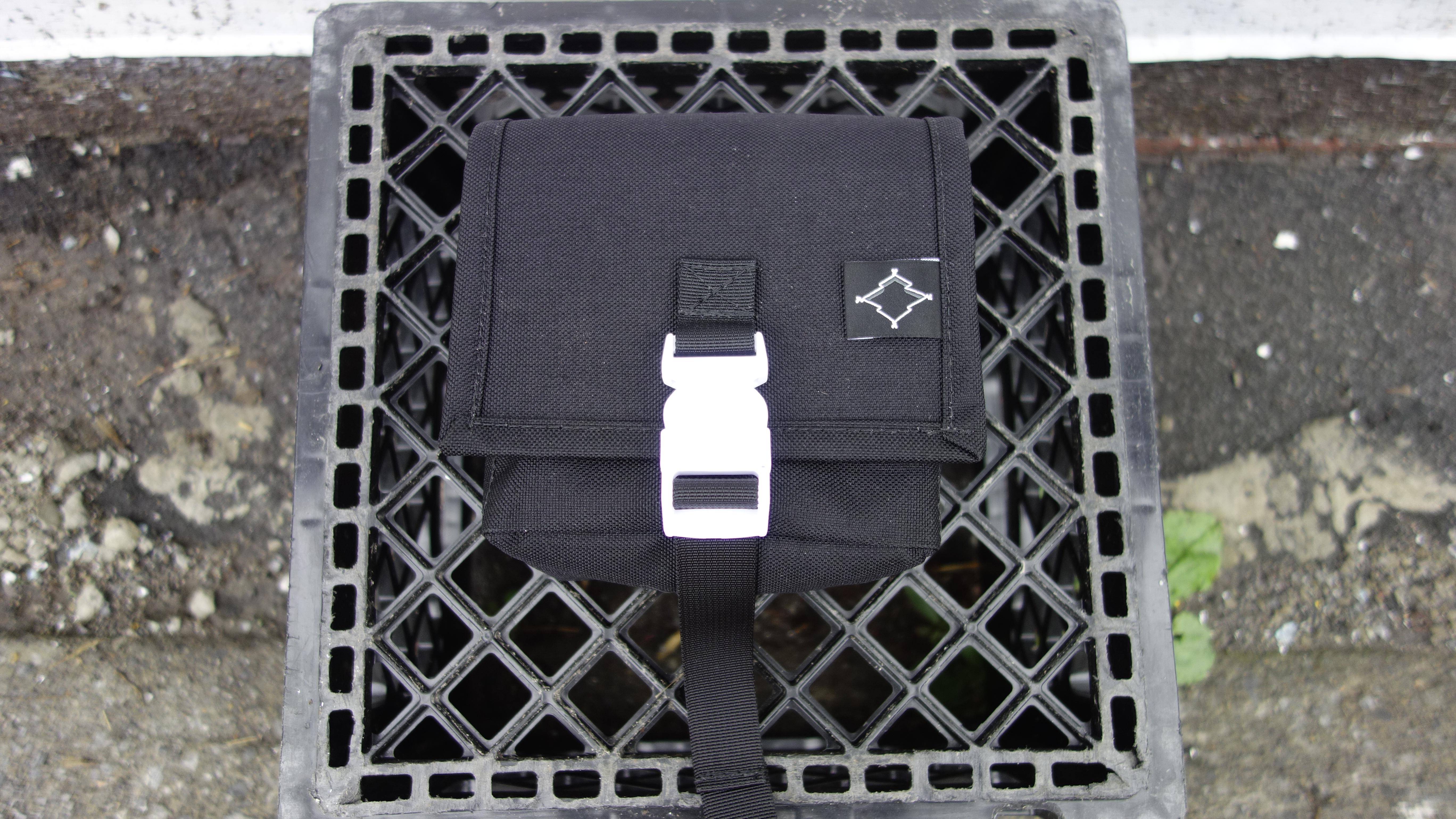 a small black square hip pouch posed on a black milk crate